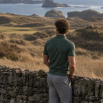 Back view of the green Deep Cypress Biome polo overlooking a coastal golf course.