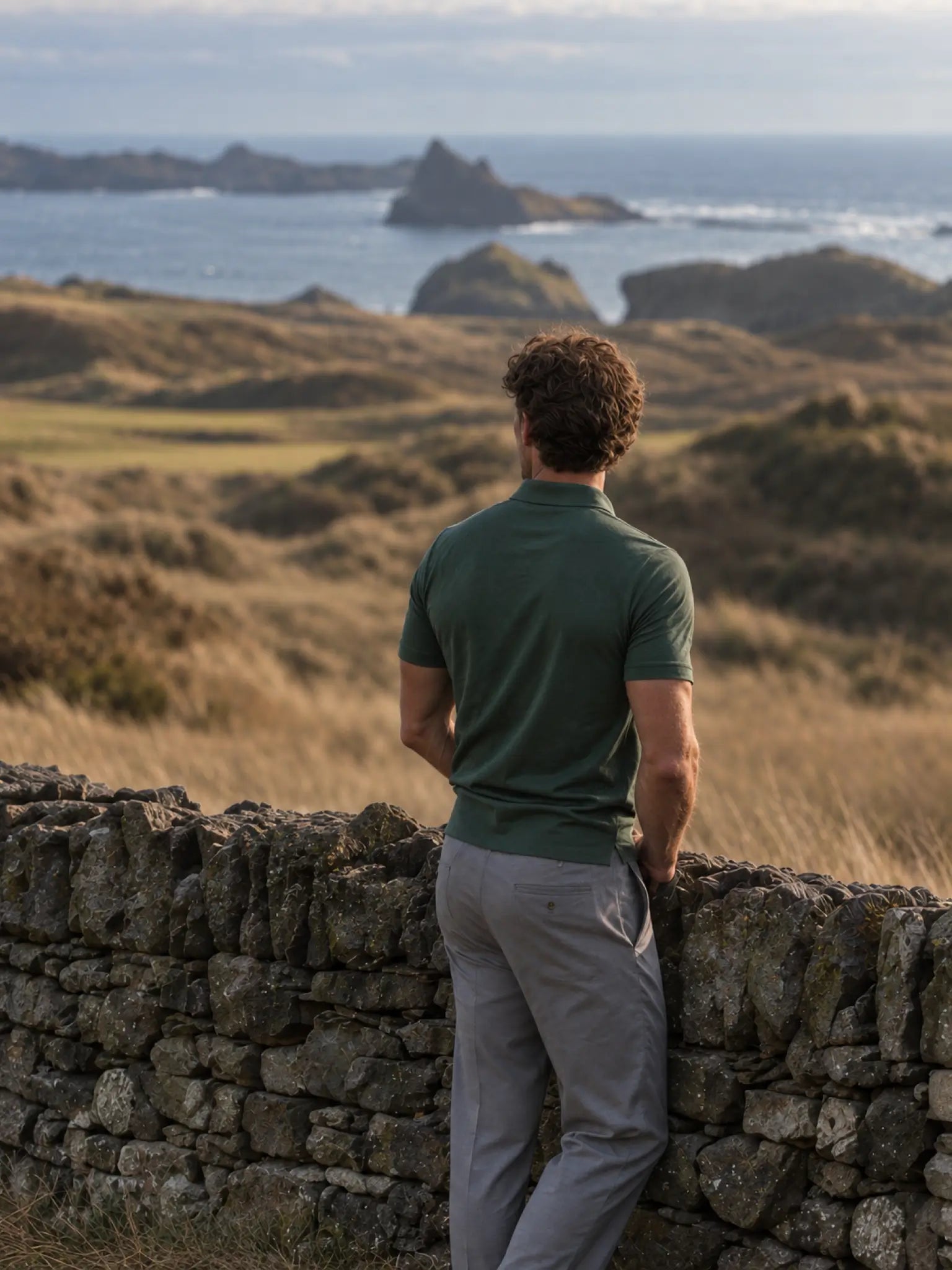 Back view of the green Deep Cypress Biome polo overlooking a coastal golf course.