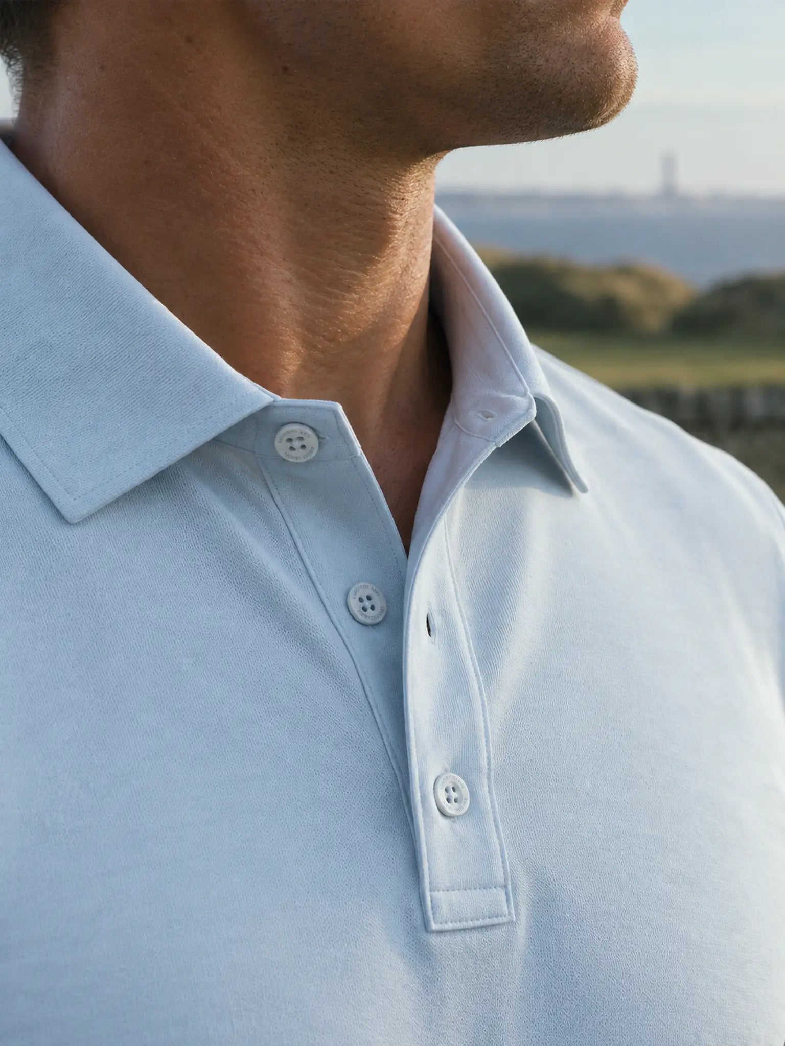 Detail of the Glacier Biome polo collar and button placket in light blue.
