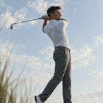 Golfer finishing a swing in the light blue Glacier Biome polo.