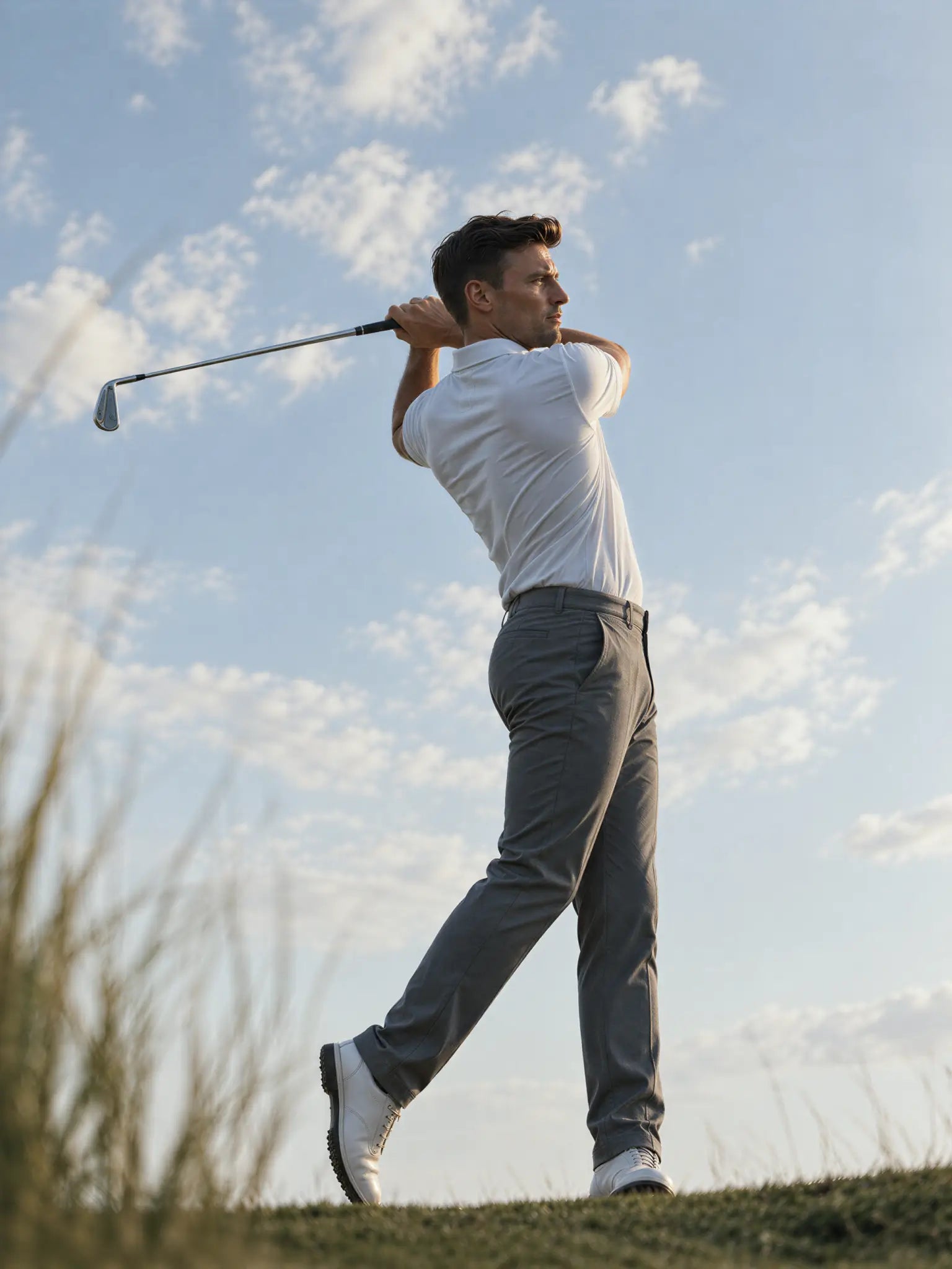 Golfer finishing a swing in the light blue Glacier Biome polo.