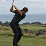 Golfer at the top of a backswing wearing the Volcanic Ash Biome polo.
