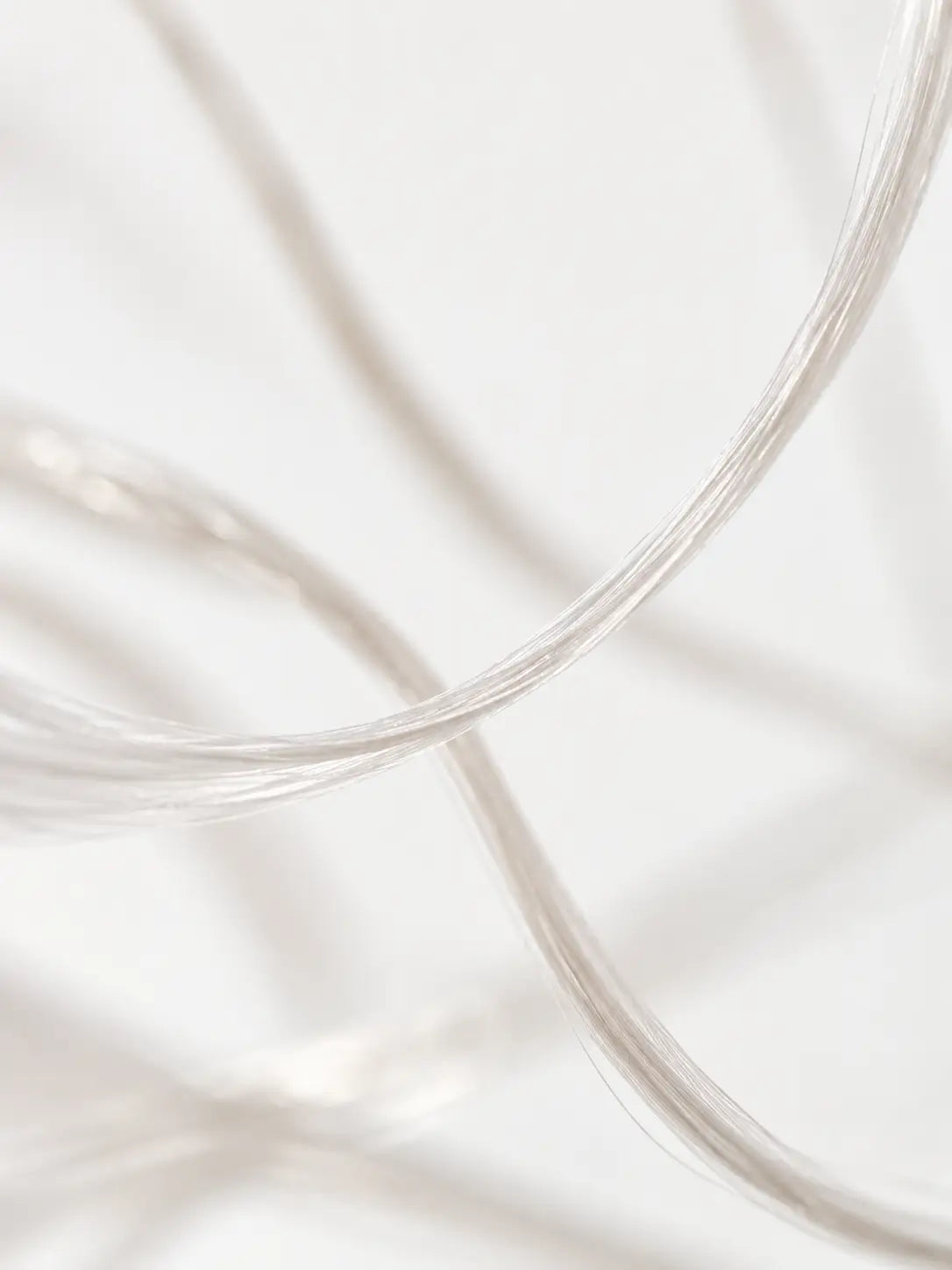 Fine pale textile strands crossing against a light background.